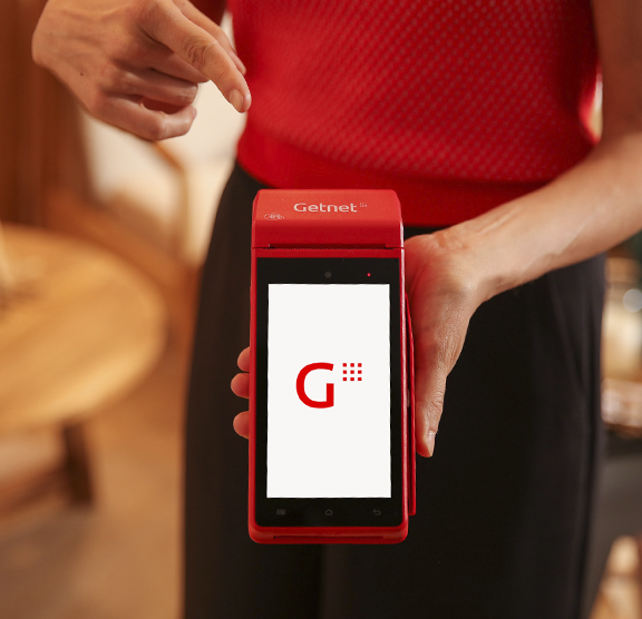 Persona sosteniendo una terminal roja de Getnet con pantalla encendida mostrando el logo de Getnet