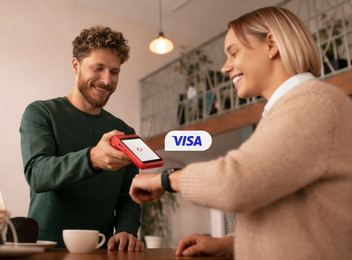 Persona acercando un smartwatch a una terminal roja de Getnet para realizar un pago con Visa.